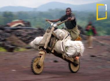 An image of a young man riding a wooden bike called a chukudu